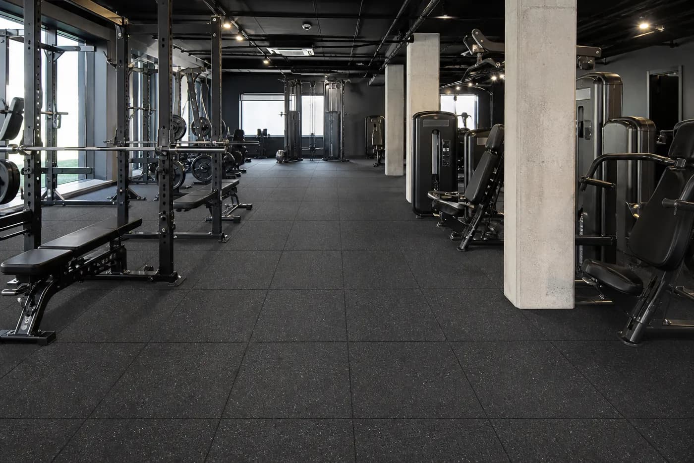 Commercial gym with speckled rubber flooring tiles and organized strength equipment