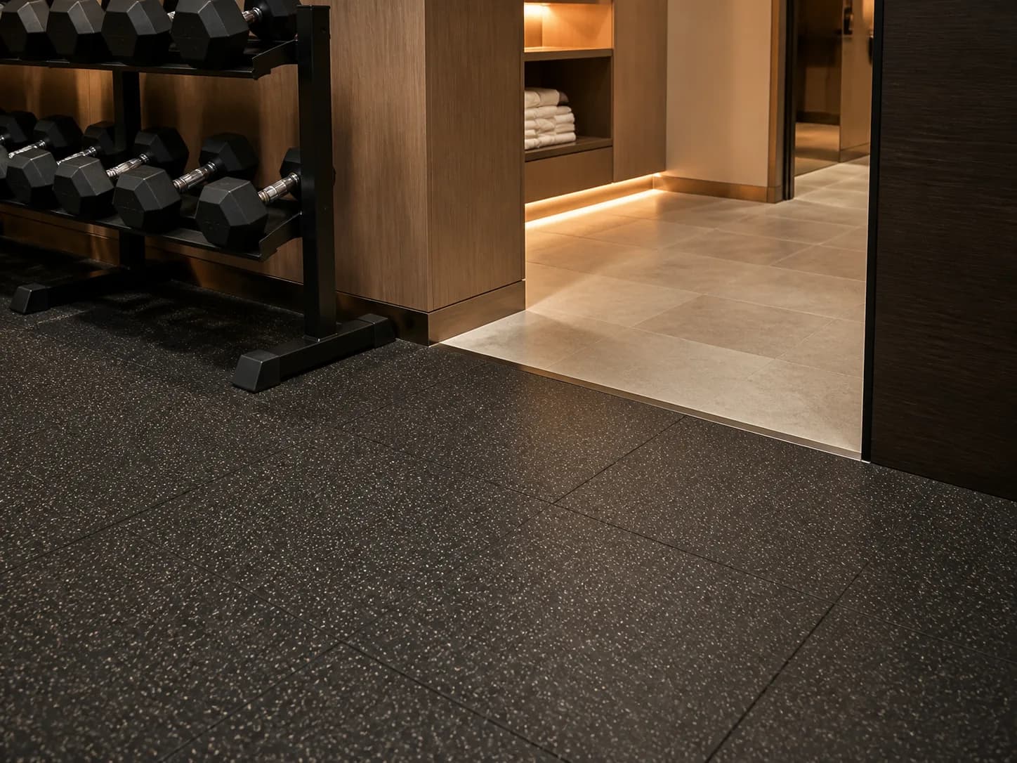 Clean transition from hotel corridor finish to speckled rubber gym tiles