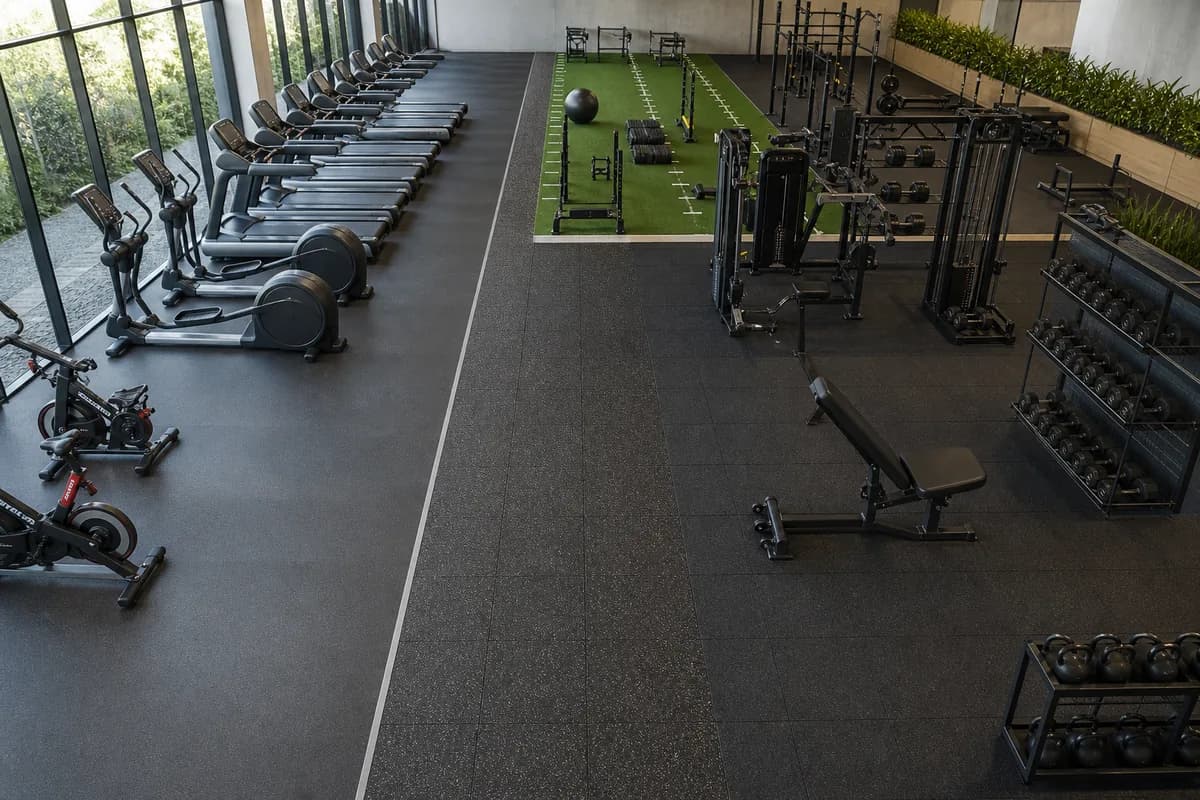 Zoned commercial gym with rubber flooring in cardio and strength areas