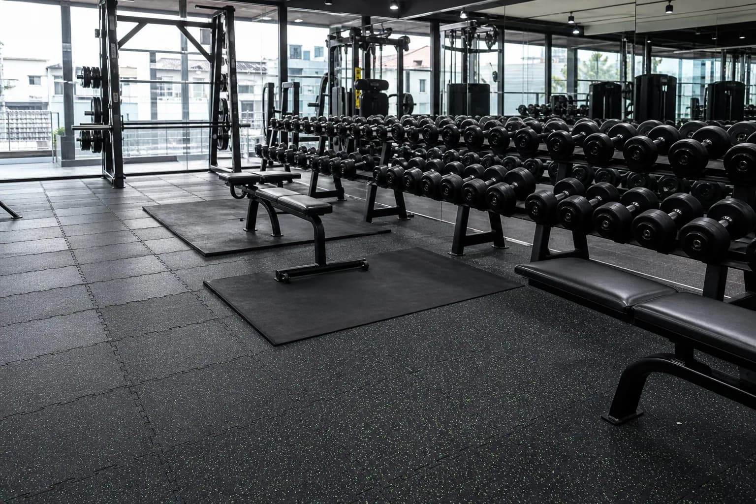 Mid-size neighborhood commercial gym: primary training zone and equipment interface using commercial interlocking rubber tiles with local heavier protection