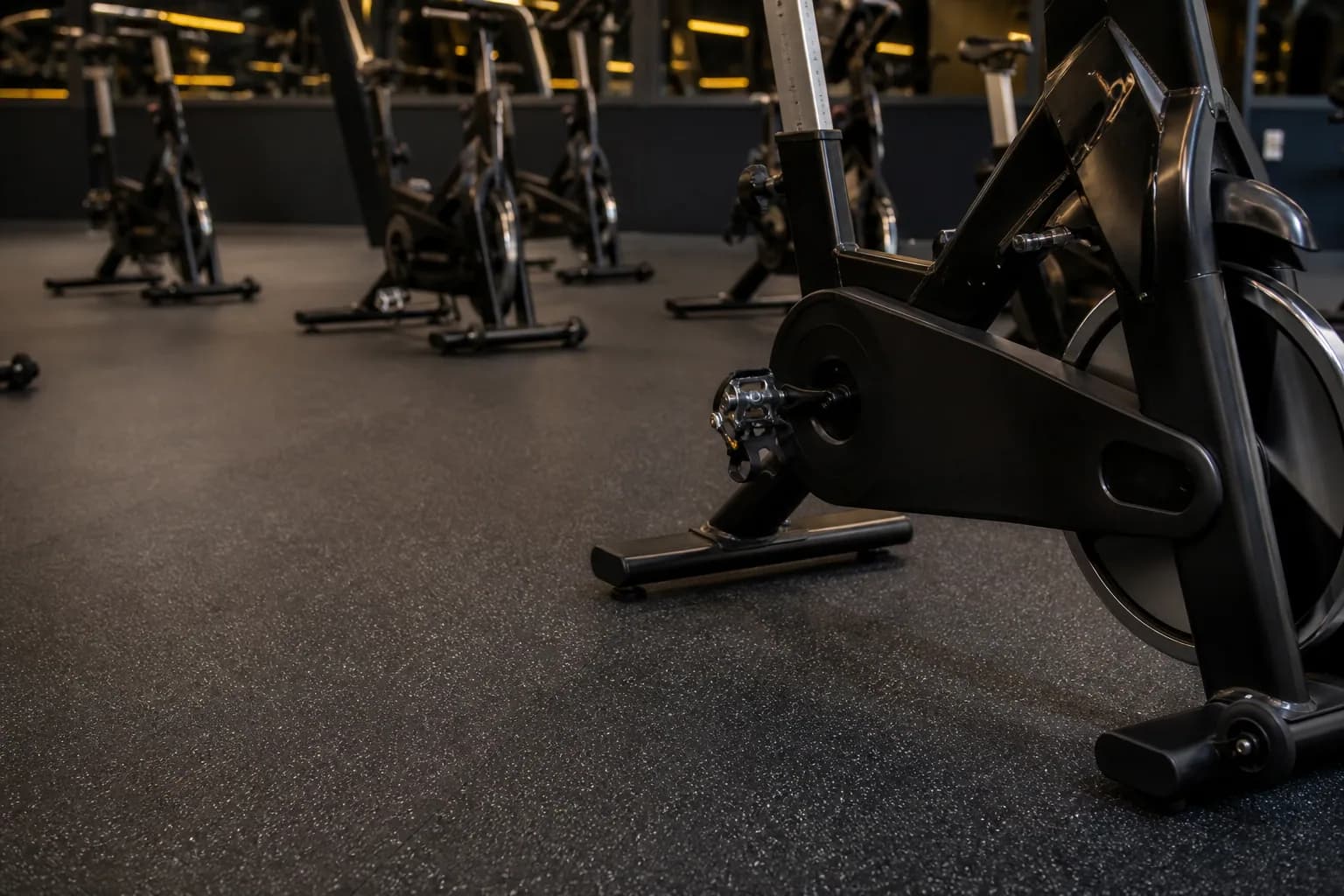 Indoor cycling studio: primary training zone and equipment interface using dense bonded rubber roll with platform and threshold details