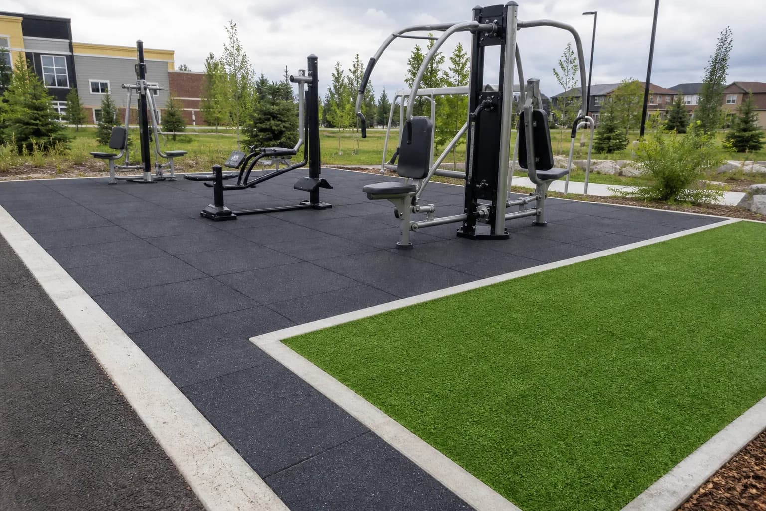 Public outdoor fitness park: primary training zone and equipment interface using weather-resistant rubber tiles and outdoor turf over a draining base