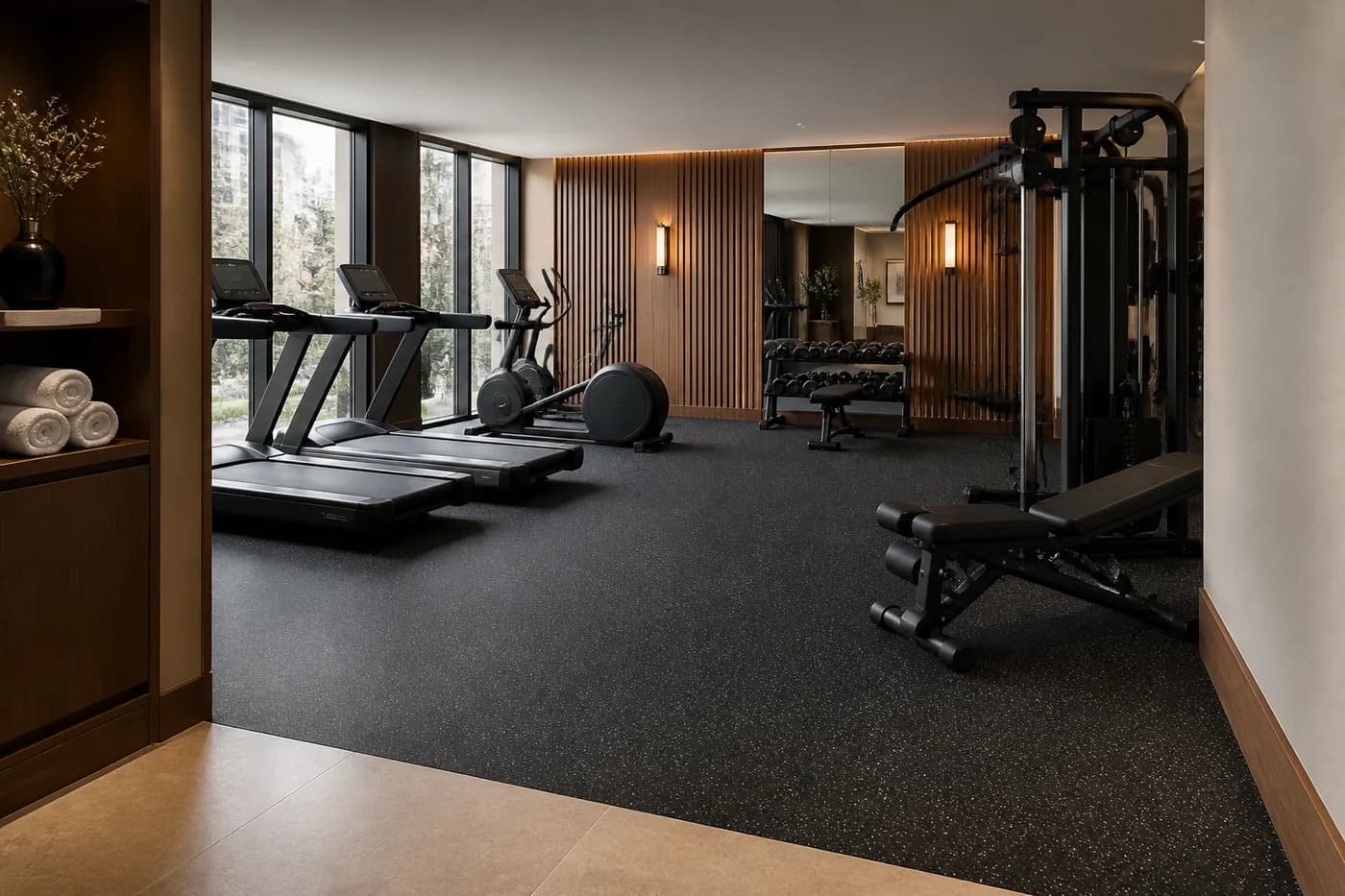 Premium hotel fitness room with refined dark rubber flooring in cardio and strength zones