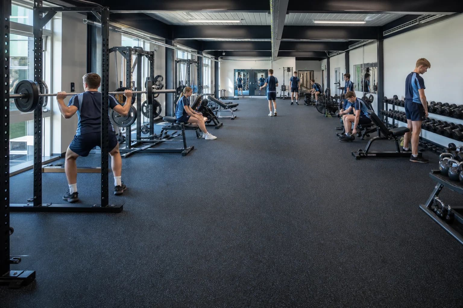 Secondary-school fitness and physical education room: completed facility and full flooring concept using durable rubber tile and roll system with supervised activity zones