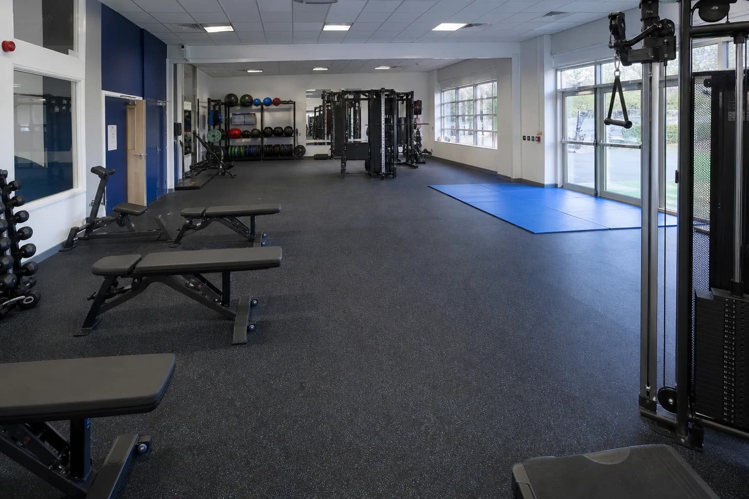 Secondary-school fitness and physical education room: overall floor zoning and circulation using durable rubber tile and roll system with supervised activity zones