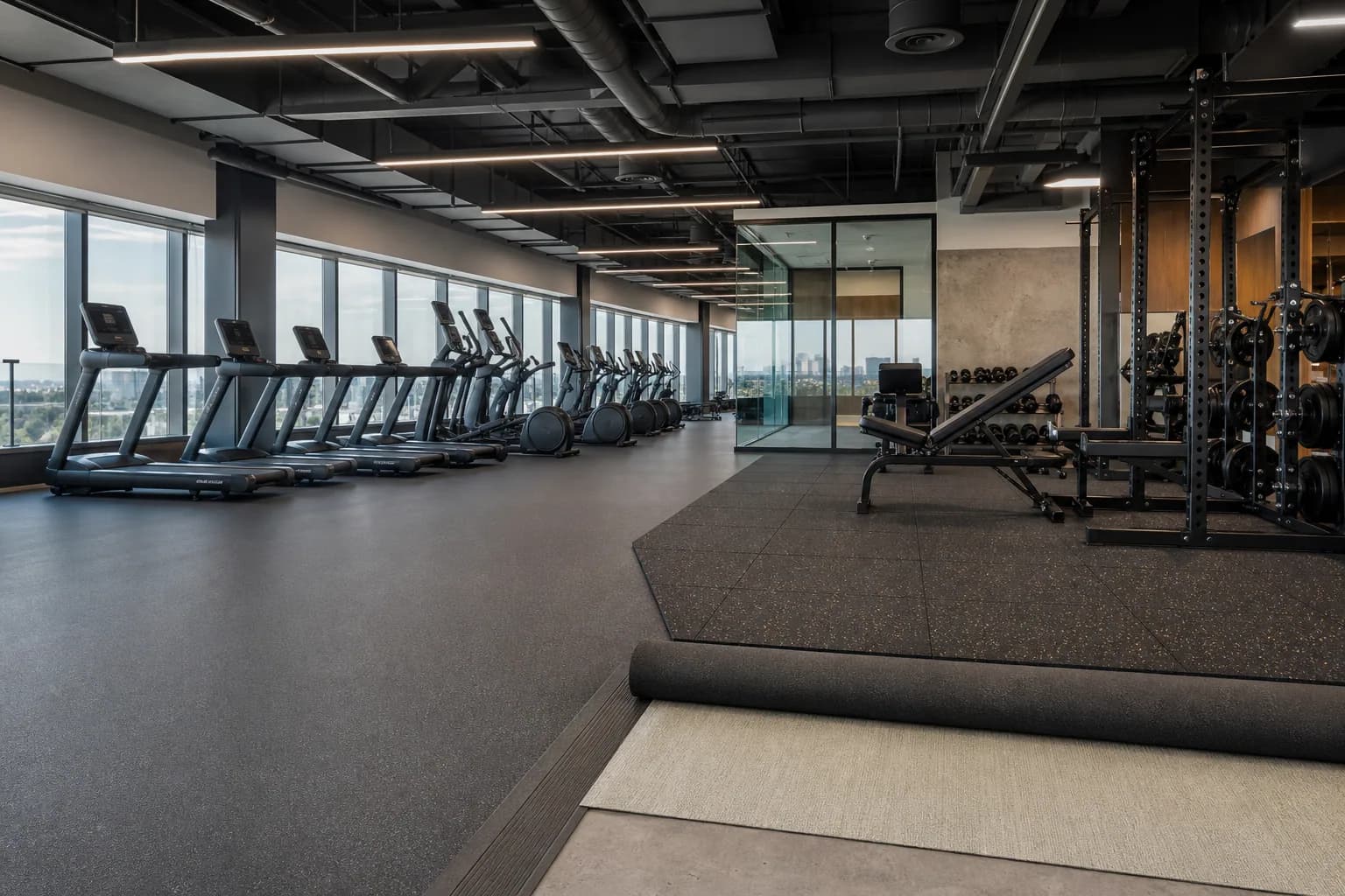 Upper-floor corporate gym above offices: completed facility and full flooring concept using source-zoned rubber surfaces and resilient underlay assemblies